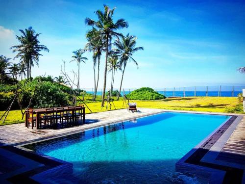 a swimming pool with palm trees and the ocean at Villa by the Sea, Negombo-Katunayake in Pamunugama
