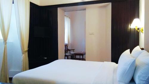a bedroom with a white bed and a room with a chair at Dutch Bungalow in Cochin