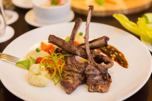 a plate of food with meat and vegetables on a table at Holiday Jazan Hotel in Jazan