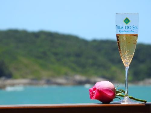 a glass of champagne and a rose on a table at Residencial Vila do Sol, Apartamentos com pé na areia in Bombinhas