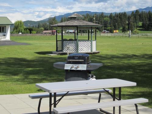 a picnic table with a grill and a gazebo at Mountain Springs Motel & RV Park in Barrière