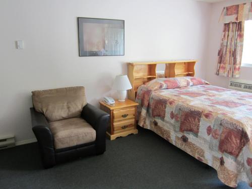 a bedroom with a bed and a chair and a lamp at Mountain Springs Motel & RV Park in Barrière