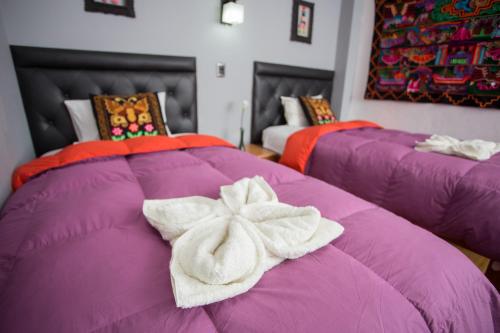 two purple beds with towels on top of them at Hotel Inka King in Ollantaytambo