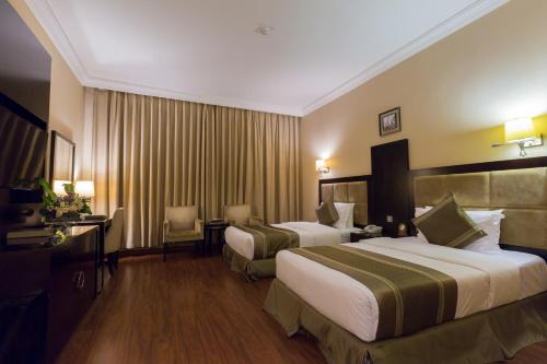 a hotel room with two beds and a desk at Holiday Jazan Hotel in Jazan