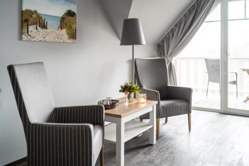 a living room with two chairs and a table at Strandhafer Aparthotel in Warnemünde
