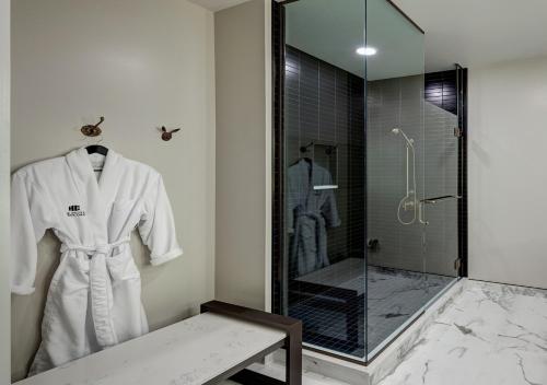 uma casa de banho com um chuveiro e um roupão branco em The Hotel Concord em Concord