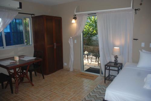 a bedroom with a bed and a desk and a bed and a window at E&J Boutique Residences in Sosúa