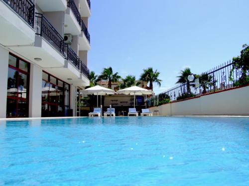 a swimming pool in a hotel with chairs and umbrellas at Albayrak Hotel in Cesme