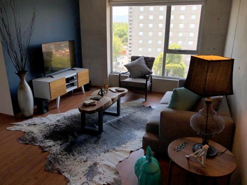 a living room with a couch and a tv at Departamento en Condesa con vista al Castillo de Chapultepec GYM - POOL - PARKING in Mexico City