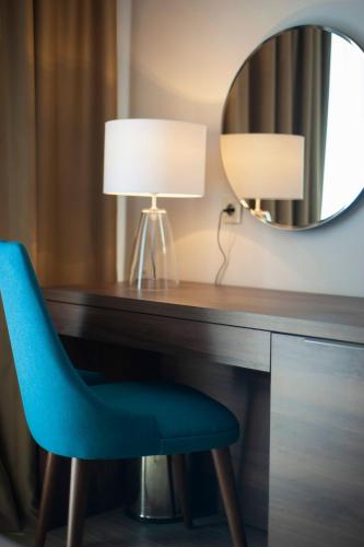 a desk with a blue chair and a mirror at Hotel Twelve by Aycon in Budva