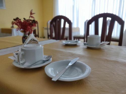 una mesa de madera con platos y utensilios. en Hotel Castilla en Villa Gesell