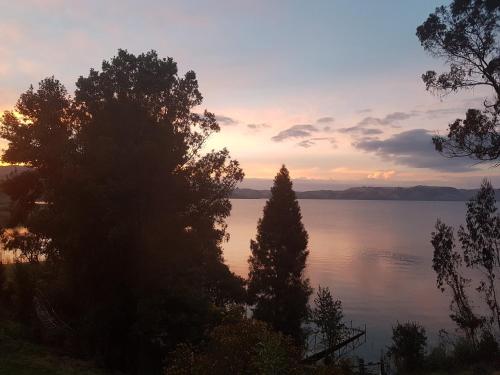 a sunset over a body of water with trees at Cabañas Yukatan Lago de Tota in Tota