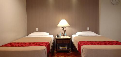 two beds in a room with a lamp between them at Tropicana Suites in Manila