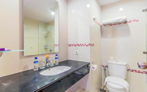 a bathroom with a sink and a toilet and a mirror at Conjioo Hotel Kuta Formerly Instyle Hotel in Legian
