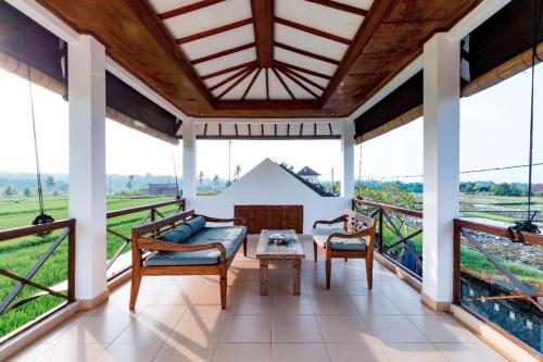 a living room with a table and chairs and windows at Medewi Surf Villa in Pulukan