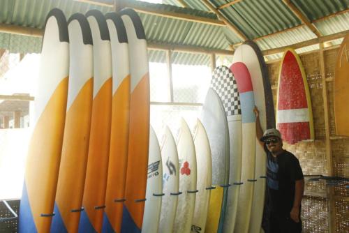 a man standing in front of a row of surfboards at Medewi Surf Villa in Pulukan