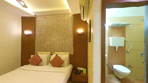 a bedroom with a bed and a sink and a toilet at Hotel Jyoti in Rajkot