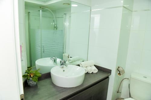a white bathroom with a sink and a toilet at Tiberias Holiday Apartment in Tiberias