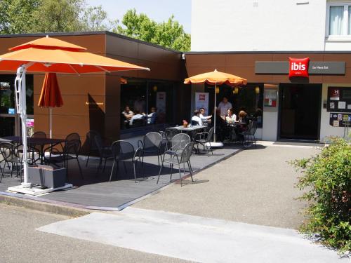 a restaurant with tables and chairs and umbrellas at ibis Le Mans Est Pontlieue in Le Mans