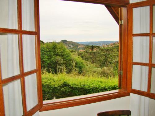 an open window with a view of a field at Alpenhaus Pousada in Campos do Jordão
