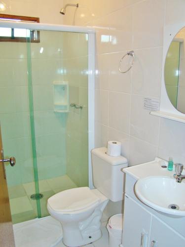 a bathroom with a shower and a toilet and a sink at Alpenhaus Pousada in Campos do Jordão