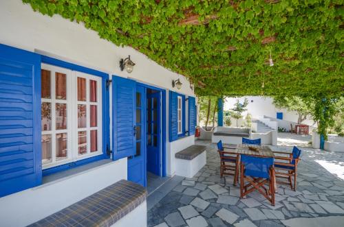 a house with blue doors and chairs on a patio at Despina Hotel in Agia Anna Naxos