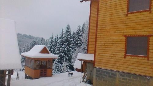 a cabin with snow on the ground next to a building at Marichka in Yablunytsya
