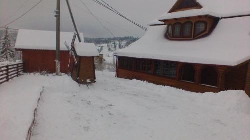 a house covered in snow next to a building at Marichka in Yablunytsya