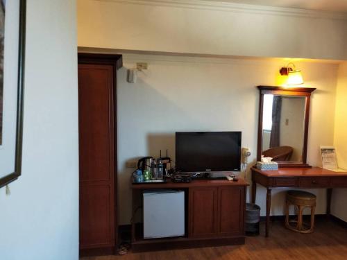 um quarto com uma televisão numa mesa com uma secretária em Little Paradise Inn em Hengchun South Gate