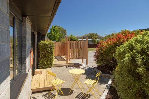 a patio with a table and chairs and a fence at The Willows Wanaka in Wanaka