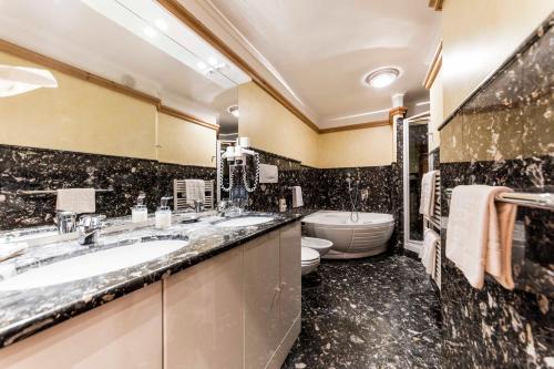 a bathroom with two sinks and a toilet at Active Hotel Ancora in Predazzo