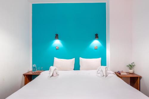 a bedroom with a large white bed with a blue wall at Ostello Bello Mandalay in Mandalay