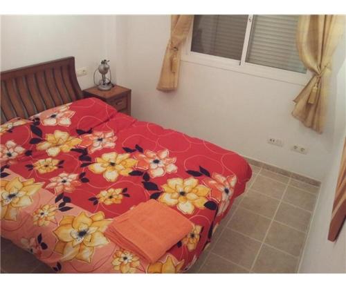 a bedroom with a red bed with flowers on it at Penthouse, Casares del Sol, Malaga in Casares