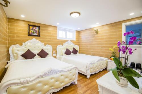 two beds in a bedroom with wooden walls at ROY VILLA COFFEE in Da Lat