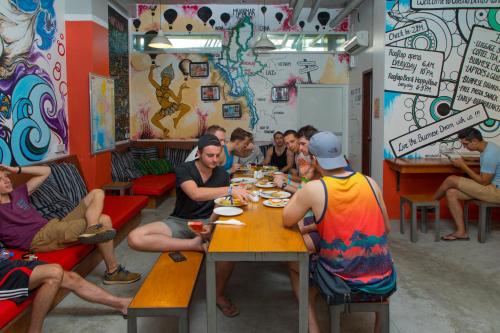 a group of people sitting at a table in a restaurant at Ostello Bello Mandalay in Mandalay