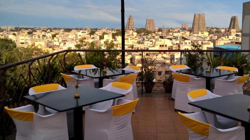 a balcony with tables and chairs and a view of the city at Hotel Supreme in Madurai