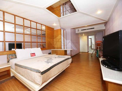 a bedroom with a bed and a desk and a television at Midi Motel Tainan Branch in Anping