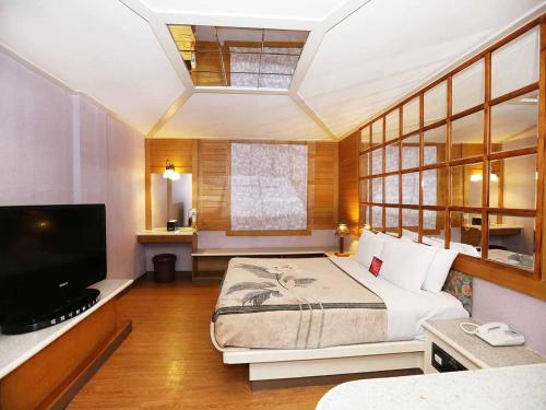 a bedroom with a bed and a flat screen tv at Midi Motel Tainan Branch in Anping