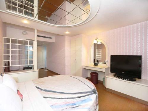 a bedroom with a large bed and a flat screen tv at Midi Motel Tainan Branch in Anping