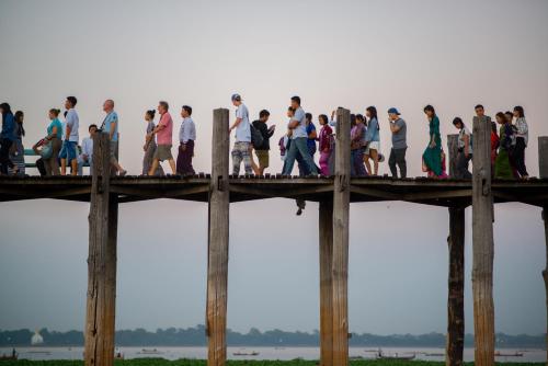 a group of people walking on a wooden bridge at Ostello Bello Mandalay in Mandalay