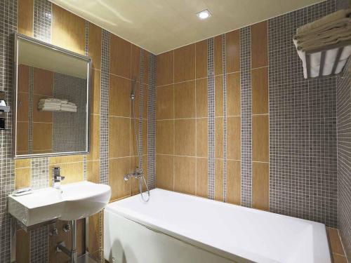 y baño con bañera, lavabo y espejo. en Royal Group Motel Buo Ai Branch, en Kaohsiung