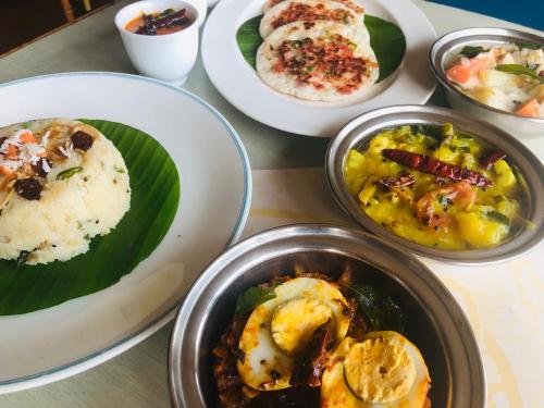 a table with plates of food and bowls of food at Hotel Abad Plaza in Cochin