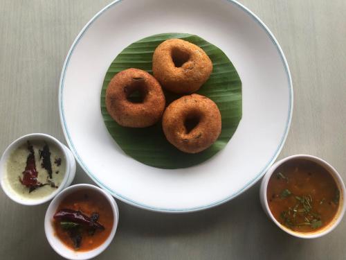 a plate with three donuts on a green leaf at Hotel Abad Plaza in Cochin