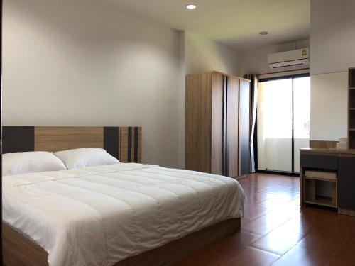 a bedroom with a white bed and a large window at Rabbit Hotel in Phetchabun