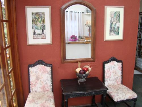 a room with two chairs and a table and mirrors at Alpenhaus Pousada in Campos do Jordão