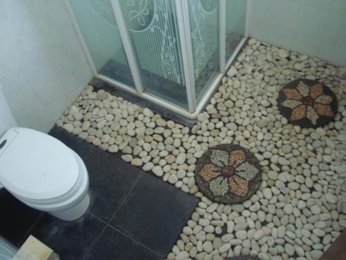 a bathroom with a shower and a toilet and rocks at Gusti Home Stay Ubud in Ubud