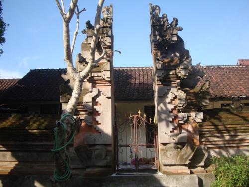 a gate to a building with a tree in front of it at Gusti Home Stay Ubud in Ubud