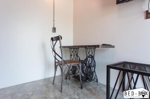 a black table and a chair in a room at Bed Box in Nakhon Ratchasima