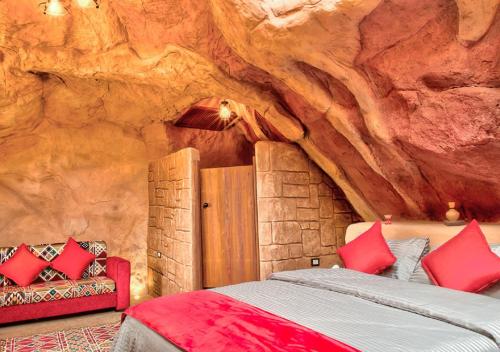 - une chambre avec un lit dans un mur de roche dans l'établissement Captains Desert Camp, à Wadi Rum
