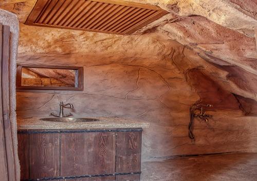 La salle de bains est pourvue d'un lavabo et d'un mur en pierre. dans l'établissement Captains Desert Camp, à Wadi Rum